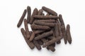 Macro close-up of Organic Indian long pepper Piper retrofractum on white background. Pile of Indian Aromatic Spice.