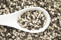 Macro Close up of Organic split black urad dal Vigna mungo with shell on a white ceramic soup spoon.