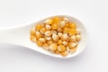 Macro Close up organic yellow corn seed or maize Zea mays on a white ceramic soup spoon.