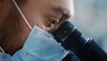 Macro Close Up Shot of a Handsome Male Scientist Wearing Medical Mask and Looking into the Royalty Free Stock Photo