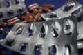 Macro close up of silver empty blisters with pile of capsules, blue background - medicines waste abuse concept