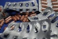 Macro close up of silver empty blisters with pile of capsules, blue background - medicines waste abuse concept