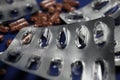 Macro close up of silver empty blisters with pile of capsules, blue background - medicines waste abuse concept