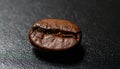 Macro close-up of single coffee bean on smooth black surface Royalty Free Stock Photo