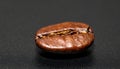 Macro close-up of single coffee bean on smooth black surface Royalty Free Stock Photo