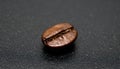 Macro close-up of single coffee bean on smooth black surface Royalty Free Stock Photo