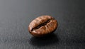 Macro close-up of single coffee bean on smooth black surface Royalty Free Stock Photo