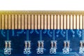 Macro close up view of a blue circuit board and row of golden connector pins