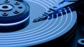 Macro close-up view of a hard drive platter with glowing blue data read head motion lines indicating rapid digital information Royalty Free Stock Photo
