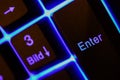 Macro closeup of blue illuminated enter key on computer keyboard