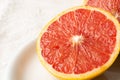 Macro closeup of half a split red grapefruit on white plate, horizontal,