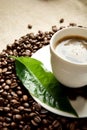 Macro cropped shot of frothy coffee with green leaf on linen cloth