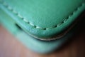 Macro detail of a green thread stitching green stitched leather case