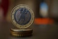 Macro detail of a metal Euro coin on the column created of coins with a positive warm background