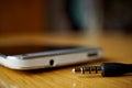 Macro detail of a metal headphone jack nearby the connector in the cellphone, on the wooden surface Royalty Free Stock Photo