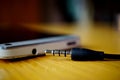 Macro detail of a metal headphone jack nearby the connector in the cellphone, on the wooden surface Royalty Free Stock Photo