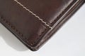 Macro detail of a white and brown thread stitching black and brown stitched leather wallet