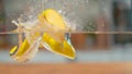 MACRO, DOF: Sweet sliced golden delicious apple falls into the glassy water. Royalty Free Stock Photo