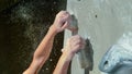 MACRO: Unknown young female climber with strong fingers hangs onto two jugs