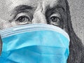 Macro 100 dollar bill shows Benjamin Franklin wearing a surgical mask to protect Covid-19 coronavirus