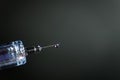 Macro of a drop of liquid that came out of a needle on a clear syringe, on black grey background Royalty Free Stock Photo