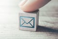 Macro Of An E-Mail Icon On A Wooden Block Arranged By A Female Finger On A Table Royalty Free Stock Photo