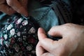 Macro elderly woman hands sewing on fabric, needle. Sew pants by old woman hand, seamstress at work with cloth fabric. Grandmother