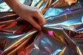 macro of fingers smoothing out a crease in shiny metallic gift wrap