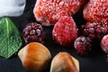 Macro frozen raspberry, blackberry, strawberries, hazelnuts mint leaves, pieces of ice on a black shale board, frozen fruit, set Royalty Free Stock Photo