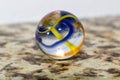 Macro of a glass marble with blue and yellow stripes