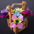 Macro Handmade colored paper flowers origami bouquet paper craft art in a basket with grass in the studio on colored