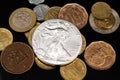 A silver American coin with coins from Pakistan on a black reflective background Royalty Free Stock Photo