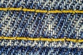 Macro image of blue jeans interwoven gold thread, denim texture background. Royalty Free Stock Photo