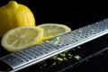 Macro image of Cheese Grater With Fresh Lemons and Lemon Zest on Wet Black Kitchen Counter Royalty Free Stock Photo