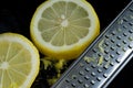 Macro Image of Cheese Grater With Fresh Lemons and Lemon Zest on Wet Black Kitchen Counter Royalty Free Stock Photo