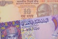 A orange ten rupee bill from India paired with a colorful one rial note note from Oman.