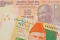 A orange ten rupee bill from India paired with a orange and green 20 rupee note from Pakistan.