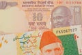 A orange ten rupee bill from India paired with a orange and green 20 rupee note from Pakistan.