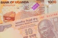 A orange ten rupee bill from India paired with a orange and white one thousand shilling bill from Uganda.