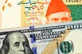 A close up image of a Pakistani rupee bank note with an American one hundred dollar bill