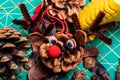 A Macro image of various pine cone reindeer being created. The pine cones are on a green cutting mat and have bright red pom-pom