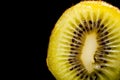 Macro kiwi cut in half on black background.