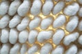 Macro of large white woven background with yellow light showing though woven fibers inbetween poofs