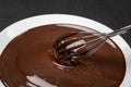 Macro of Melted milk or dark chocolate swirl in plate and whisk on concrete background Royalty Free Stock Photo