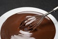 Macro of Melted milk or dark chocolate swirl in plate and whisk on concrete background Royalty Free Stock Photo