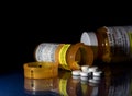 Macro of oxycodone opioid tablets with prescription bottles against dark background