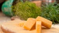 MACRO: Parmesan flakes fall down on the cheese cubes served on wooden board. Royalty Free Stock Photo