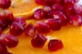 Macro peeled ripe pomegranate fruit with many slices of orange f