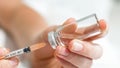 Macro image of female doctor`s hands holding ampule with medication and filling syringe