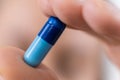 macro photo of hand holding blue pill. medical capsule, supplement or antibiotic, pharmaceutical concept Royalty Free Stock Photo